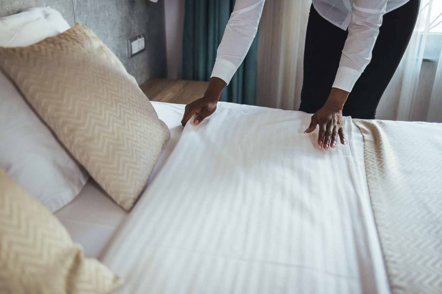 Woman pulling back the sheets of her hotel bed to inspect for signs of bed bugs
