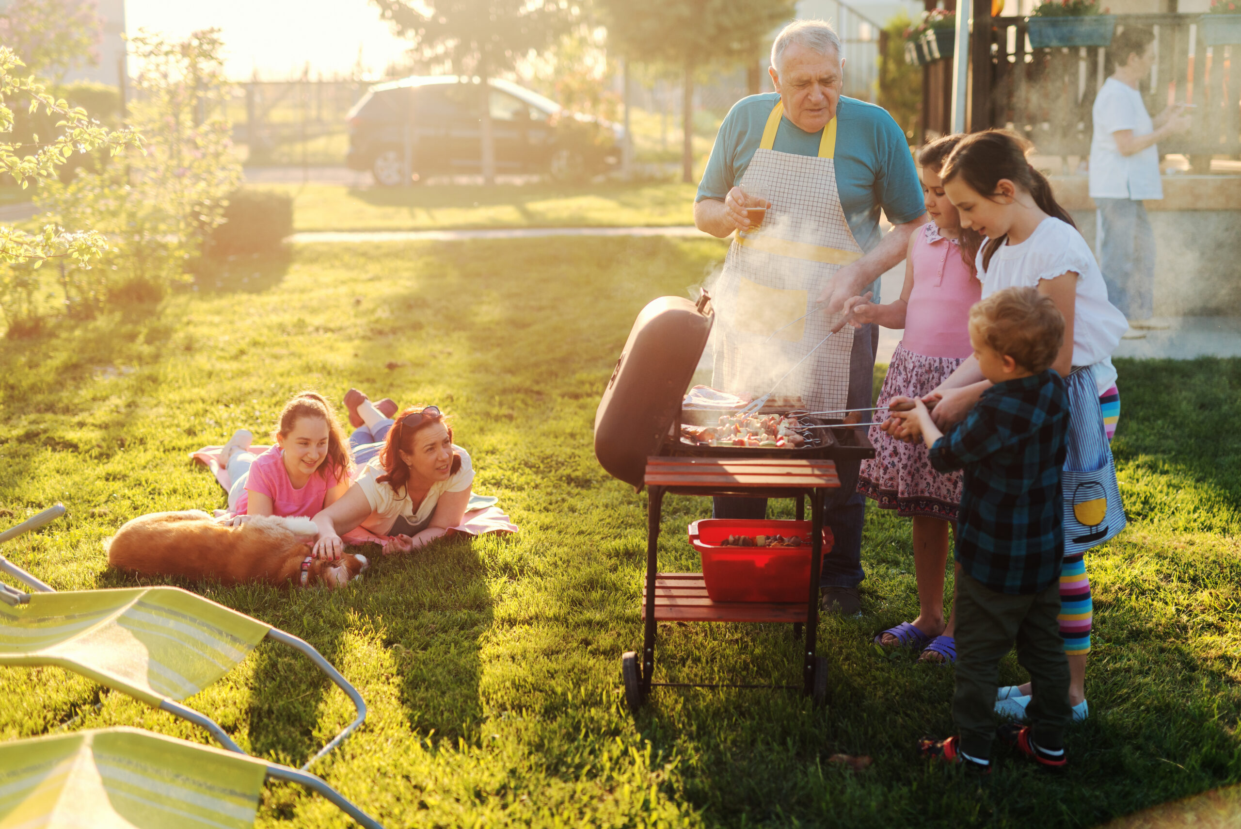 Grandfather teaches his grandchildren how to grill food at a backyard BBQ without any pesky mosquitoes
