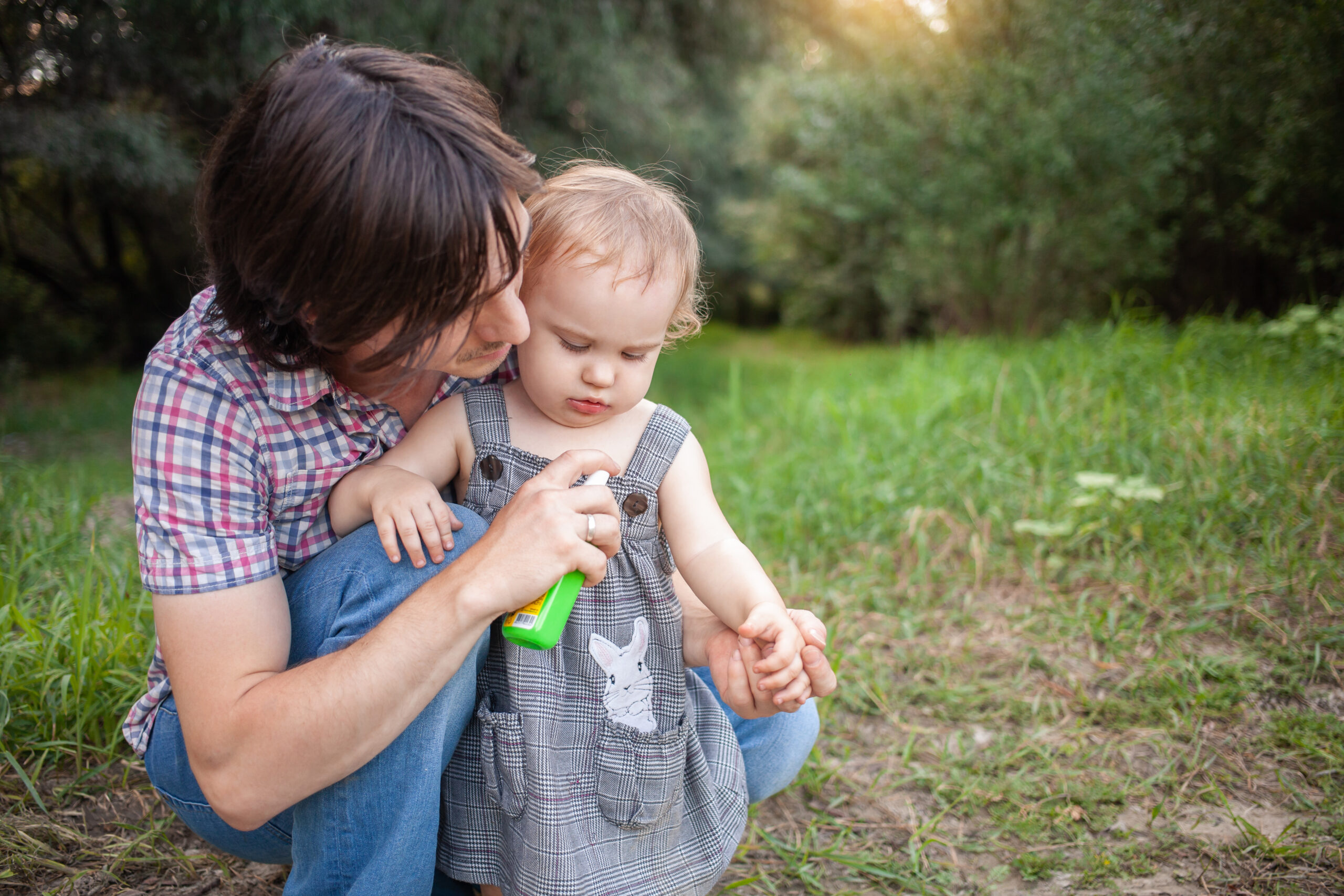 Man sprays a safe insect repellent onto his toddler