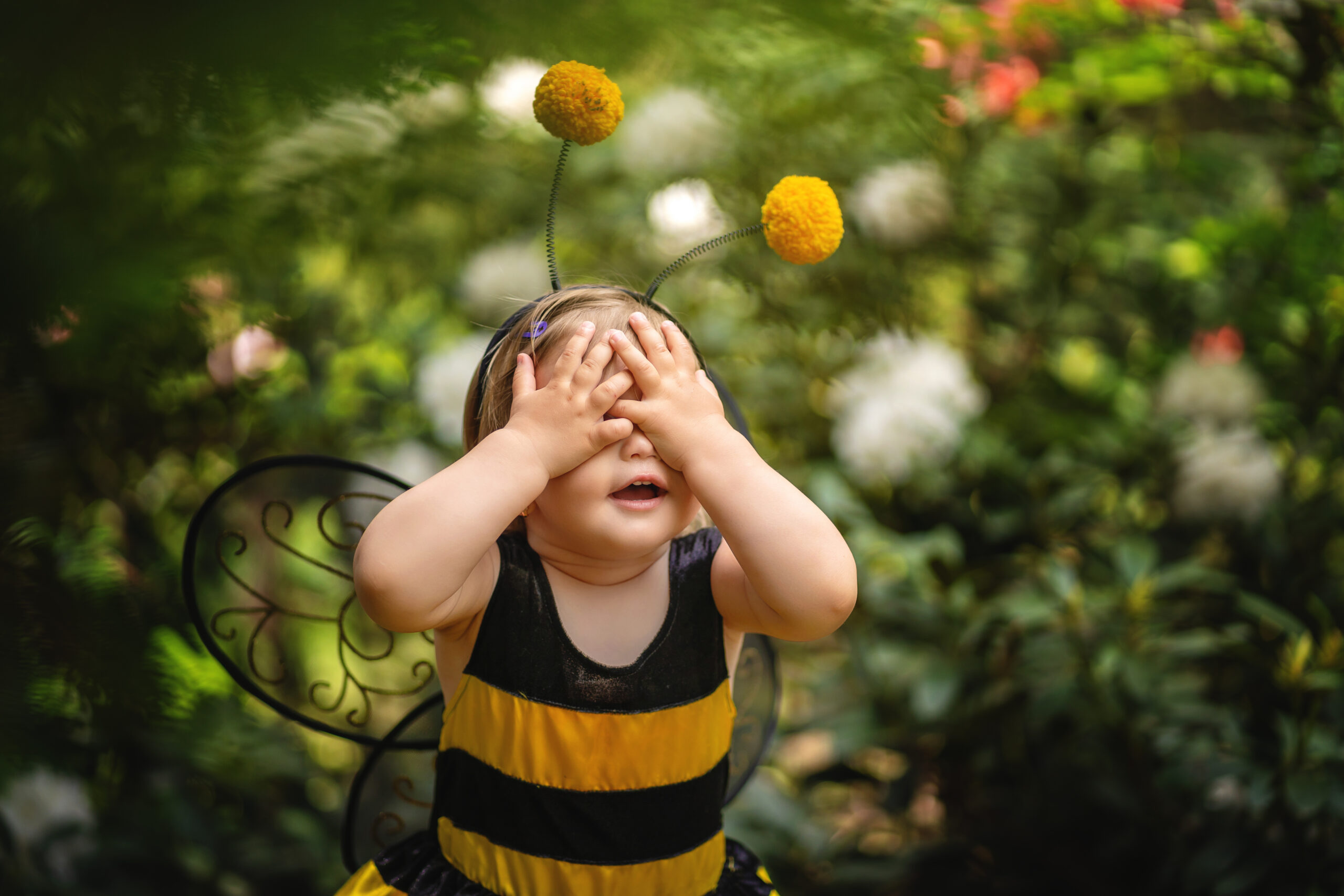Baby girl in bumblebee costume covering her eyes with hands